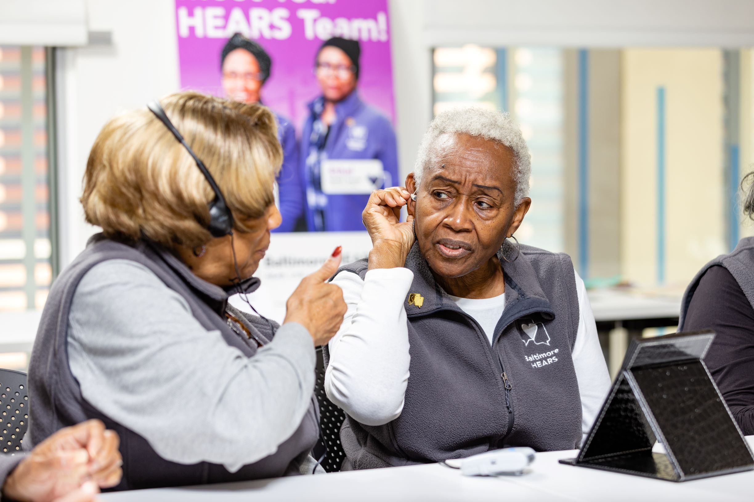 Community Health Workers demonstrate how they teach people to use a hearing aid. 