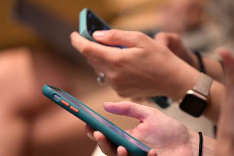 Photo of several people's hands holding smartphones